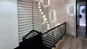 Un interior moderno con techo inclinado, una escalera con barandilla metálica e iluminación empotrada.
