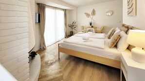 A bedroom with a bed, bedside table, lamp, and a window with curtains. - Charming apartment by the harbor with free bed linen package and terrace - (Neustadt in Holstein)
