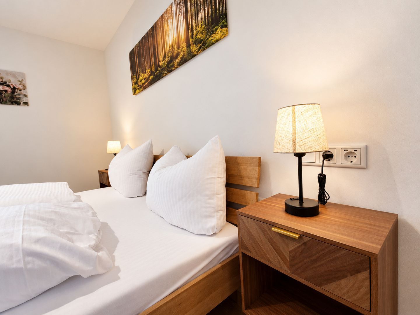 Une chambre d’hôtel avec un lit, des oreillers, une table de chevet avec une lampe et un tableau au mur.