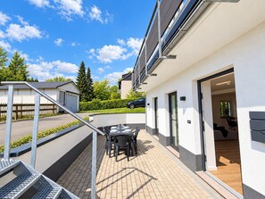 A modern residential building with a patio area featuring a table and chairs, a staircase, and a car parked in the background. - Wiesengrün Vacation Apartment: 97 m², terrace, 2 bathrooms, Wi-Fi, dogs allowed - Smart (Winterberg)