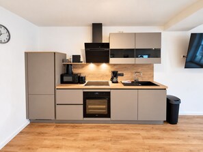 Eine moderne Küche mit Einbauofen, Mikrowelle, Kaffeemaschine und Spüle.