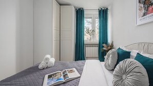 A neatly arranged bedroom with a bed, pillows, a book, and a window with curtains. - Lumina apart with balcony in Warsaw (Warsaw)