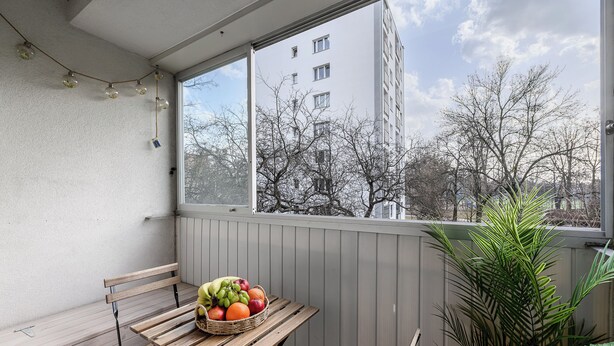 A balcony with a wooden table, a wicker basket of fruit, and a potted plant. - Lumina apart with balcony in Warsaw (Warsaw)