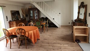 Zona pranzo con tavolo e sedie in legno, una scala e un armadietto in legno.