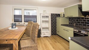 A kitchen with a wooden dining table, wicker chairs, a white refrigerator, and green cabinets. - The perfect vacation home for families in Winterberg for up to 20 people - with plenty of space, comfort and a cozy terrace (Winterberg)