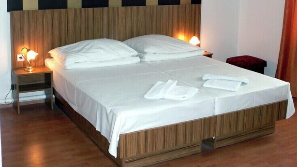 Ein Hotelzimmer mit einem großen Bett, einem Holz-Kopfteil, zwei Nachttischlampen und einem roten Sessel.