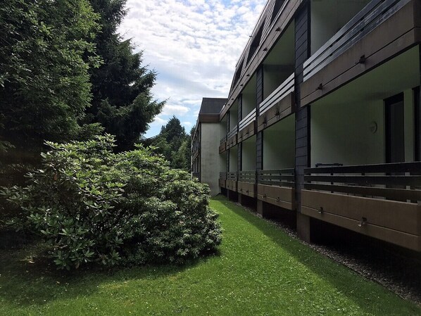 Un edificio moderno con césped verde y abundante arbustal.