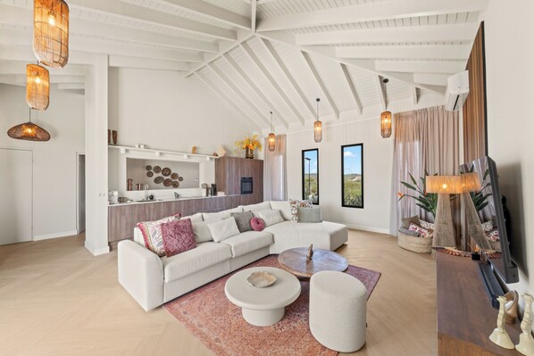 A modern living room with a sectional sofa, a coffee table, and a TV stand.