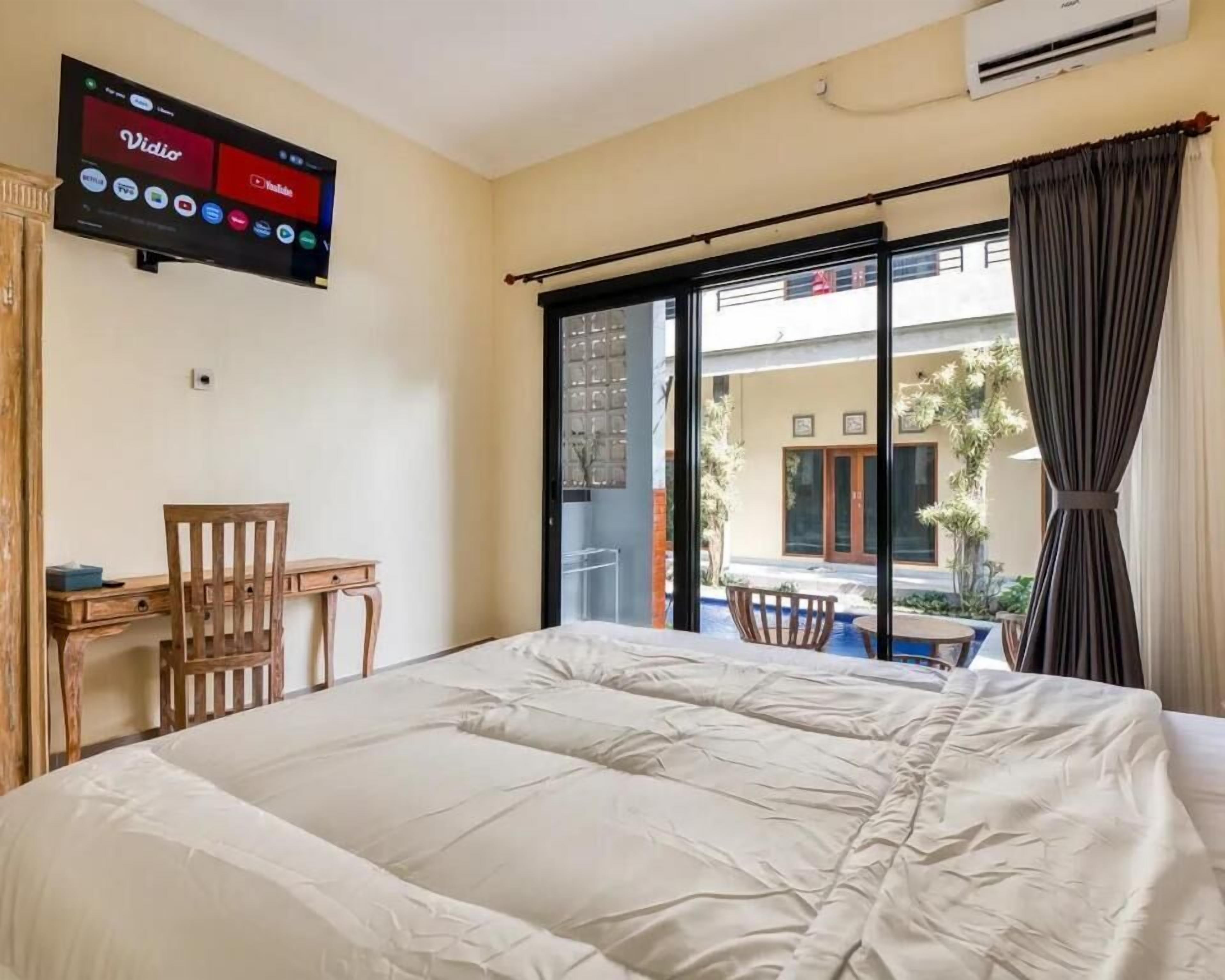 A hotel room with a bed, a desk, and a TV displaying various streaming services.