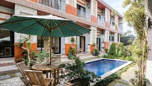 A courtyard with a pool, outdoor seating, and a variety of plants. - Dhita Kubu Guest House (Kerobokan)