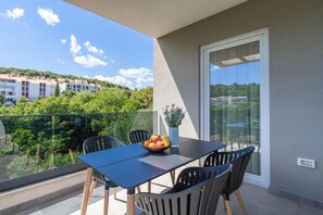 A balcony with a table and chairs, a bowl of fruit, and a potted plant. - THE SIGNATURE SUITE by DuHomes (Dubrovnik)