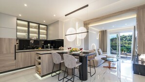Een moderne keuken met een centraal eiland, ingebouwde apparatuur en een eethoek met een ronde tafel en stoelen.