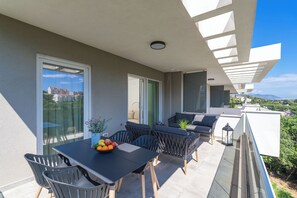 A balcony with a dining table, chairs, and a fruit bowl. There is a sofa and a small table with a plant. - THE SIGNATURE SUITE by DuHomes (Dubrovnik)
