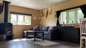A cozy living room with a sofa, a coffee table, a fireplace, and a window with curtains. - Villa Ragunda: Peace, space and Swedish adventure in the heart of Jämtland. (Hammarstrand)