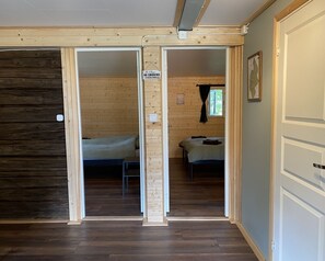 Huoneessa on kaksi sänkyä, puulattia ja kyltti, jossa lukee: ”Tupakointi kielletty”.
