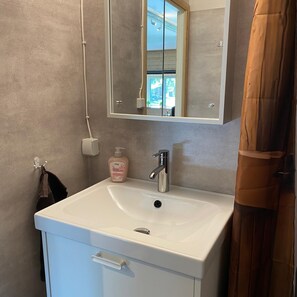 A bathroom with a white sink, a mirror, and a shower curtain. - Villa Ragunda: Peace, space and Swedish adventure in the heart of Jämtland. (Hammarstrand)