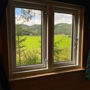 A window with a view of a green field and trees. - Villa Ragunda: Peace, space and Swedish adventure in the heart of Jämtland. (Hammarstrand)