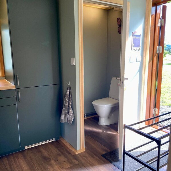 A compact bathroom with a toilet, a towel hanging on the wall, and a cabinet. - Villa Ragunda: Peace, space and Swedish adventure in the heart of Jämtland. (Hammarstrand)