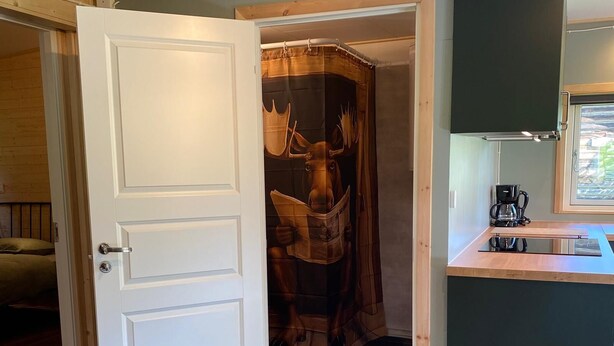 A room with a wooden door, a coat closet with a deer head decoration, and a kitchenette with a coffee maker. - Villa Ragunda: Peace, space and Swedish adventure in the heart of Jämtland. (Hammarstrand)