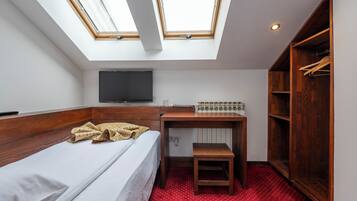 Une petite chambre comprenant un lit, un bureau, une télévision et une armoire.