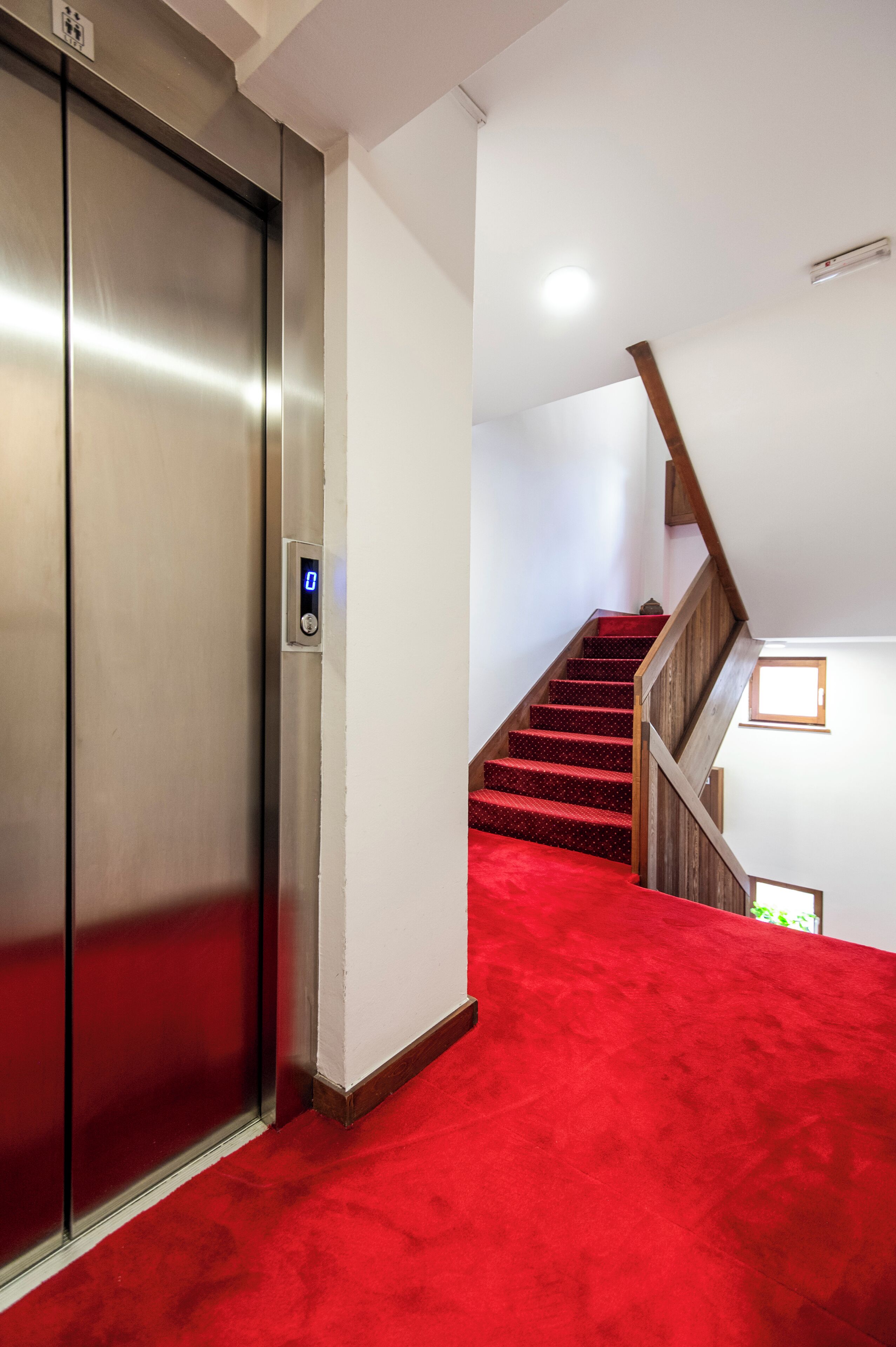 A red carpeted staircase leading to a wooden railing.
