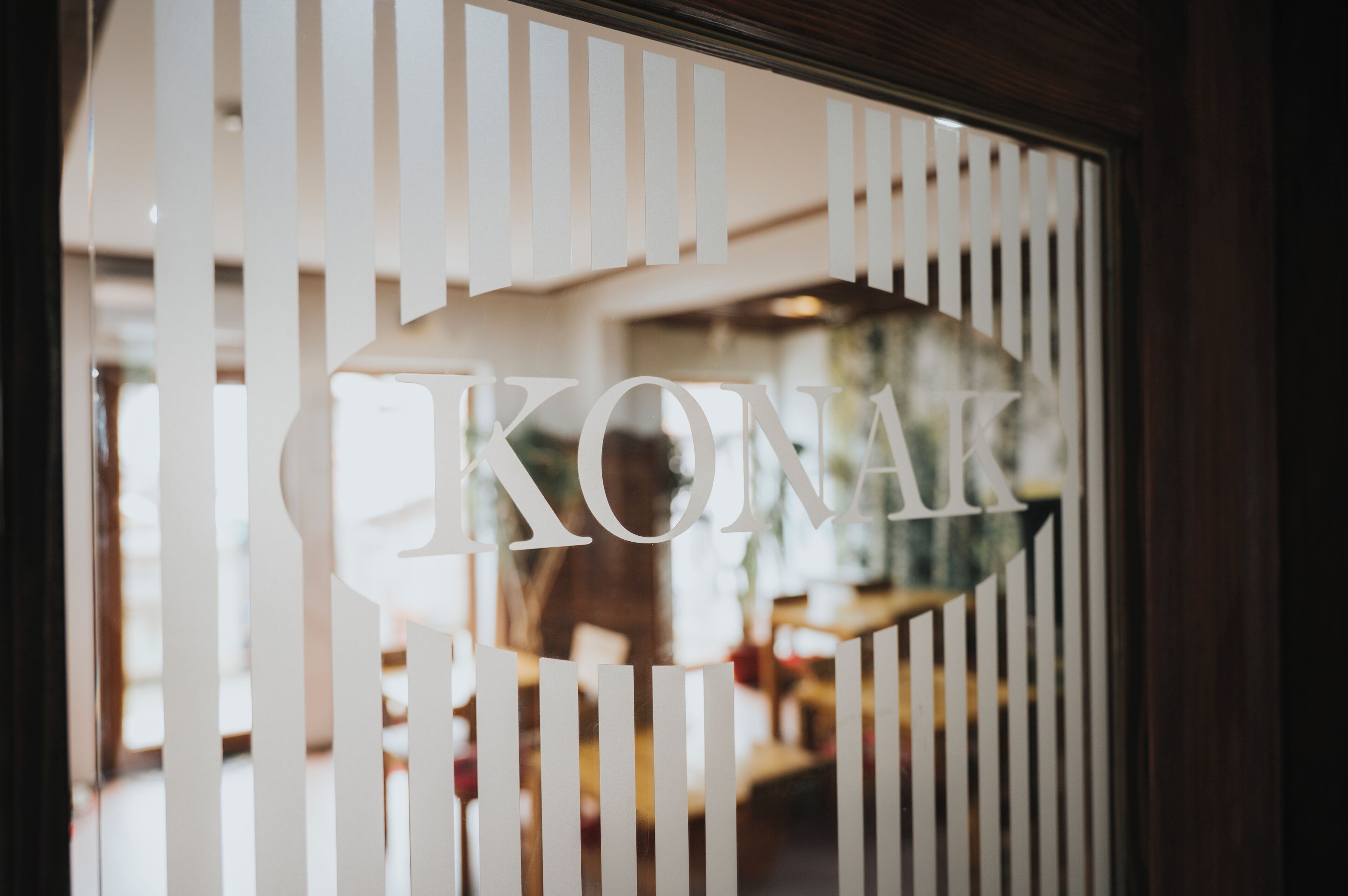 A window with vertical blinds and the word "KONAK" partially visible through the blinds.