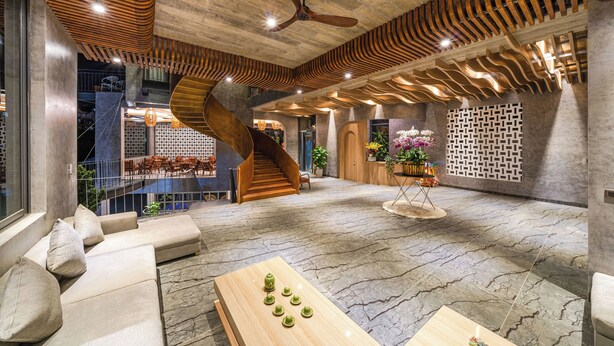 A spacious lobby with a curved staircase, a ceiling fan, and a seating area with a wooden table. - Tournesol Villa (Xuan Huong - Da Lat)