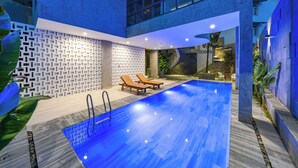 A modern indoor swimming pool with a geometric wall design, lounge chairs, and a staircase leading to an upper level. - Tournesol Villa (Xuan Huong - Da Lat)