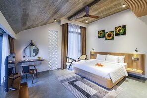 Une chambre d’hôtel moderne équipée d’un grand lit, d’un bureau avec un ordinateur, d’une chaise et d’un ventilateur de plafond.