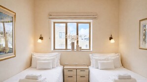 Een hotelkamer met twee bedden, een raam met uitzicht en bedlampjes.