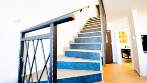 A staircase with alternating blue and beige steps, a metal railing, and a wooden handrail. - Resort Trcol (Novalja)