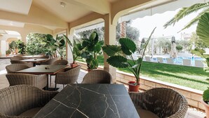 An outdoor patio area with wicker furniture, potted plants, and a view of a swimming pool. - Resort Trcol (Novalja)