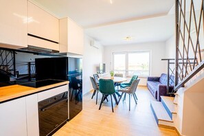 Una cocina moderna con comedor, suelo de madera y una escalera que lleva a una sala de estar.