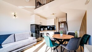 A modern living room with a sofa, a dining table with chairs, and a kitchen in the background. - Resort Trcol (Novalja)
