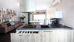Una cocina moderna con una isla integrada, un comedor y una sala de estar con sofá y cuadros.