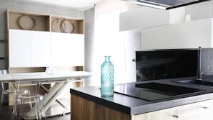 Cocina moderna con una isla central, microondas integrado y comedor con sillas transparentes.