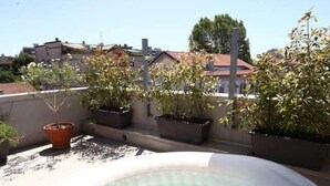 Un jacuzzi exterior con techo de madera, rodeado de plantas en macetas.
