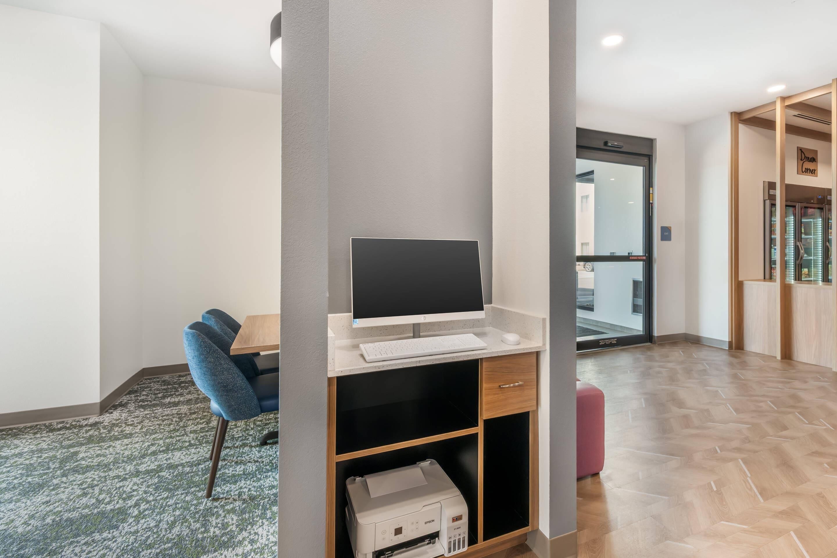A modern office space with a desk, computer, printer, and a chair.