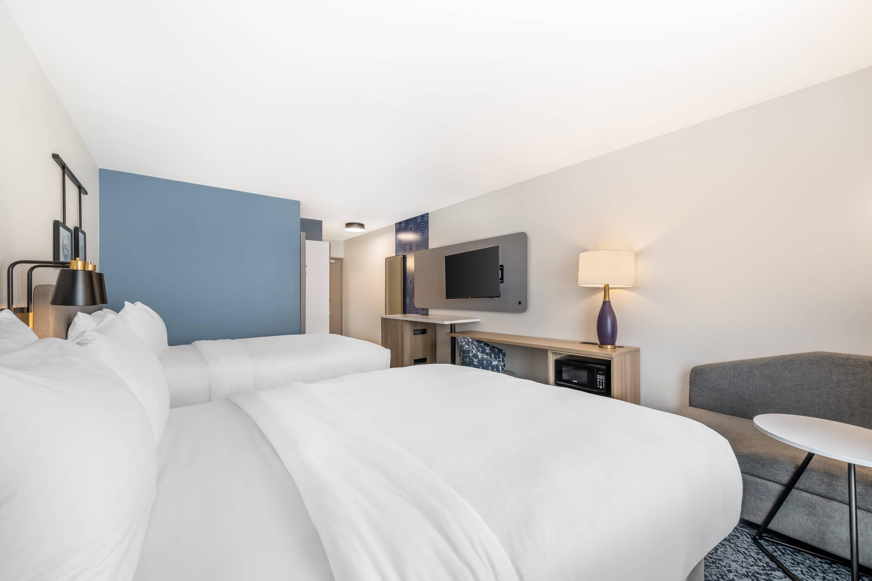 A hotel room with a large bed, a desk, a television, and a small table.