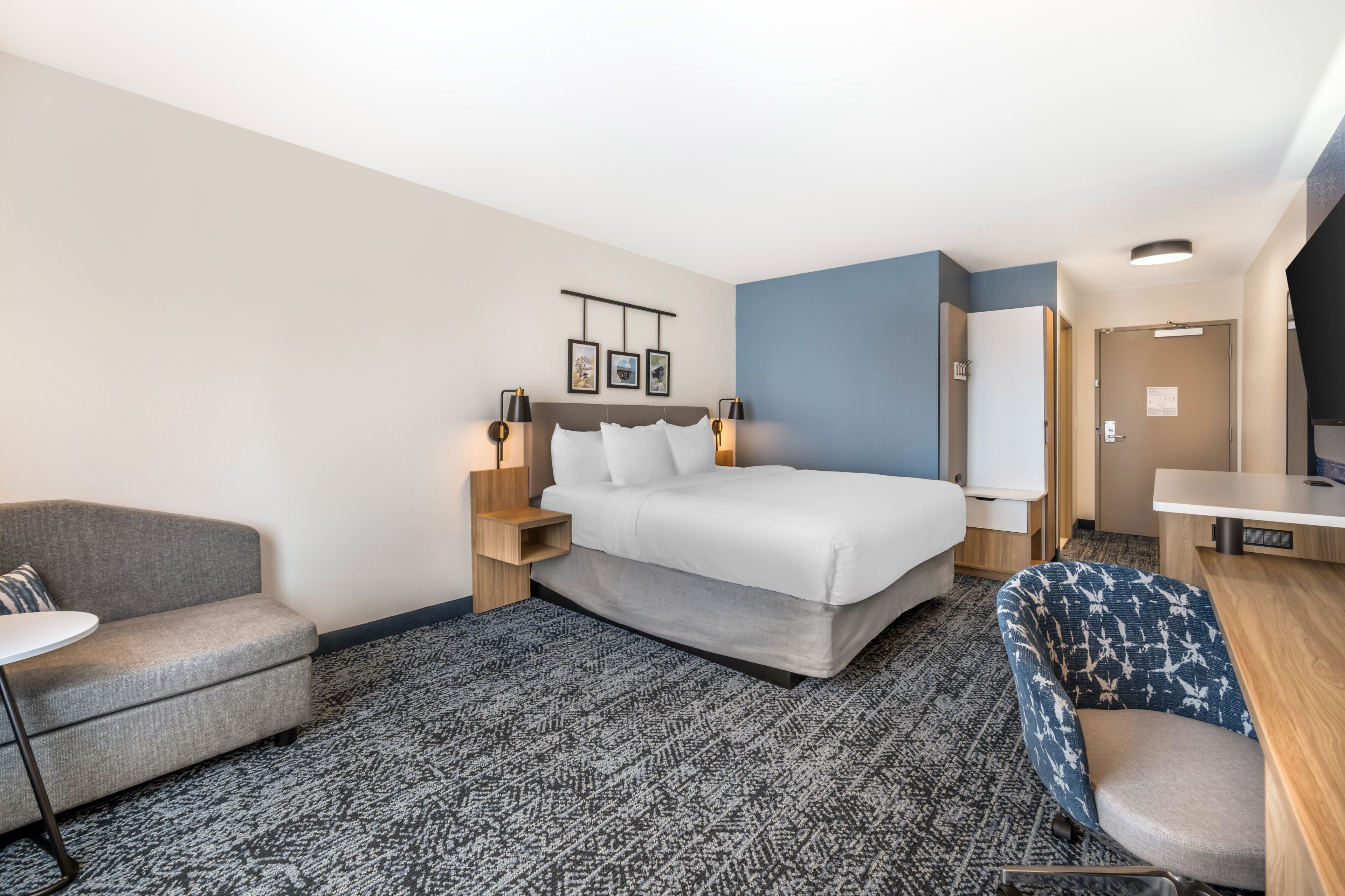 Una habitación de hotel con cama, sofá, escritorio y una silla.