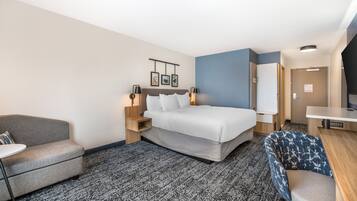 Una habitación de hotel con cama, sofá, escritorio y una silla.
