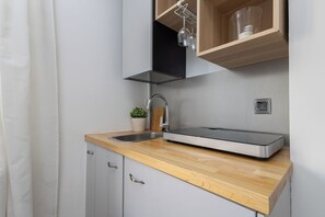 A modern kitchen with a wooden countertop, a stainless steel sink, and a built-in oven. - New World Apartament (Warsaw)