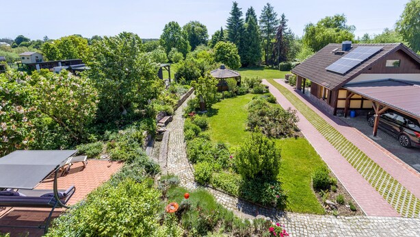 Ein Wohnhaus mit Garten, einem Pavillon, einer überdachten Terrasse und einer Solaranlage auf dem Dach.