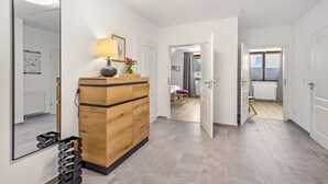 Ein modernes Interieur mit einem Holzkabinett, einem Spiegel und einer Lampe.