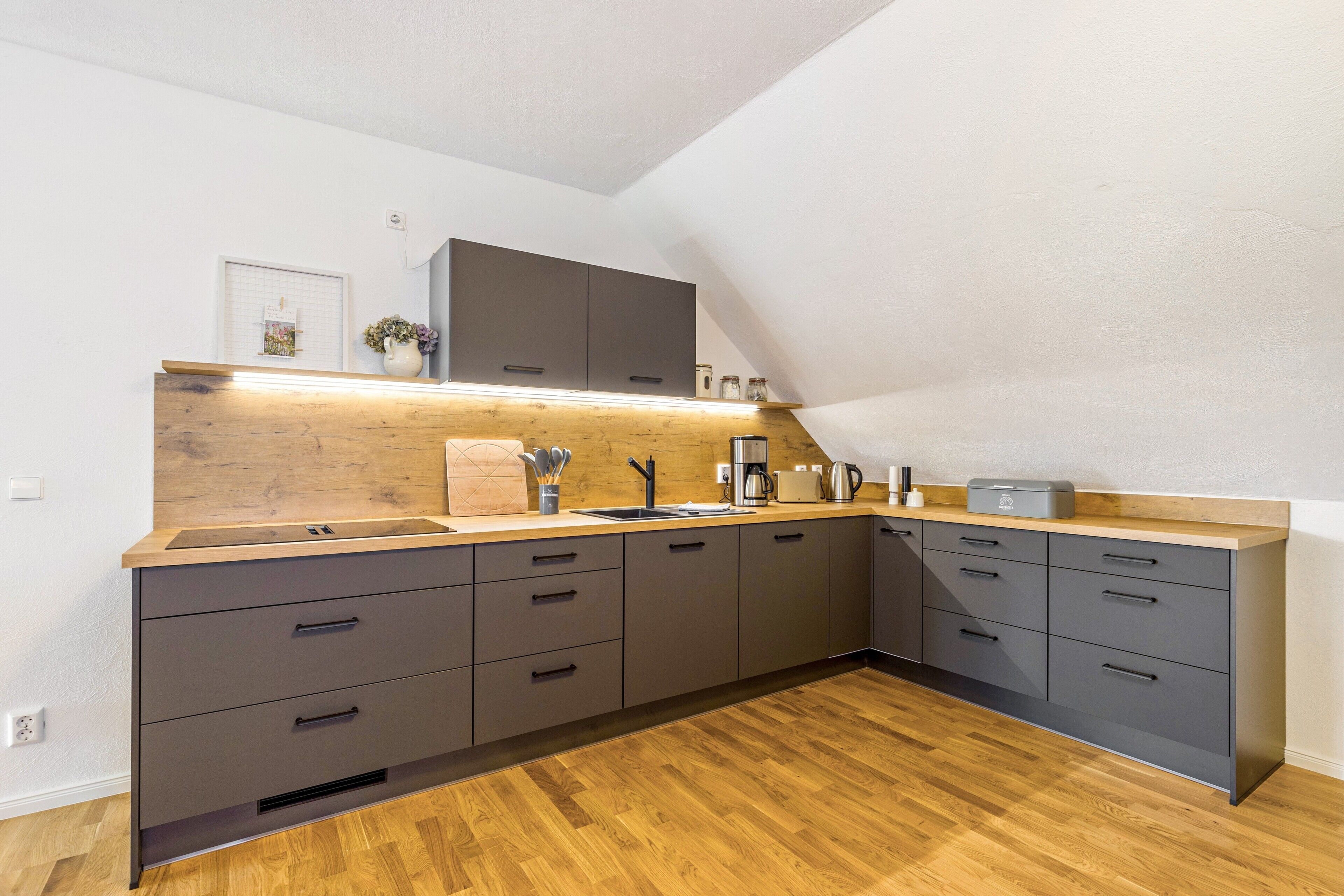 Una cocina moderna con encimera de madera, armarios grises y horno integrado.
