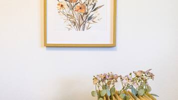 A framed botanical illustration and a stack of books with flowers on a white wall.