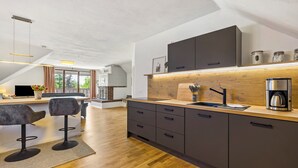 Eine moderne Küche mit Holzarbeitsplatte, dunklen Schränken und einer Kaffeemaschine.