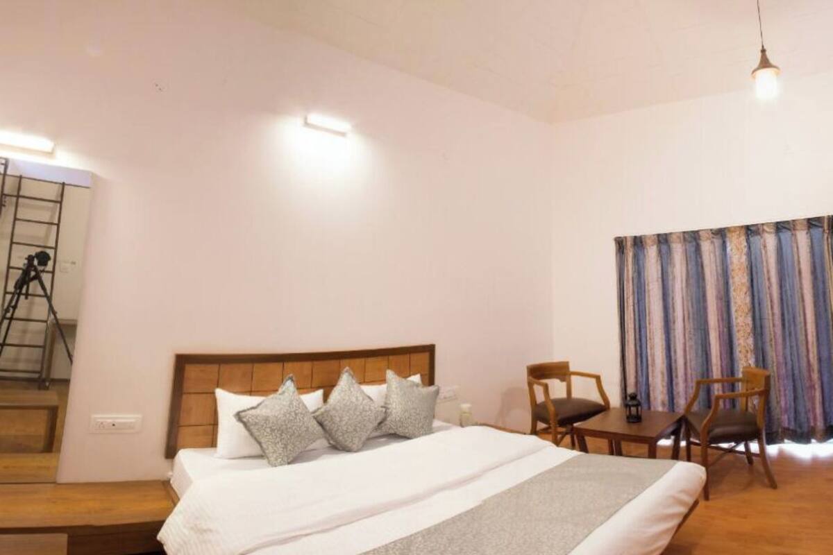 A hotel room with a bed, a desk, a chair, a television, and a staircase.