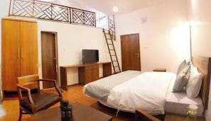 A bedroom with a bed, a desk, a chair, a wardrobe, and a TV. - Kabila Agro Tourism (Mahabaleshwar)