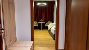 A hotel room with a wooden wardrobe, a small table with chairs, a bed, and a circular ceiling light.